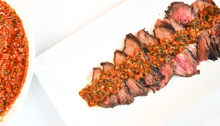 Chimichurri Rojo sauce draped across red meat.