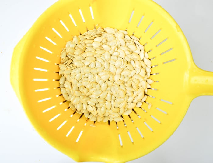 Rinsed pumpkin seeds in colander.