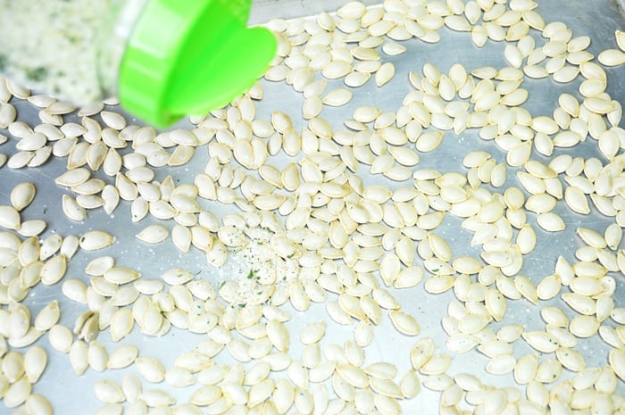 Pumpkin seeds being dashed with garlic salt.